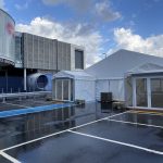 Temporary warehouse buildings set up on a paved car park near an event venue.