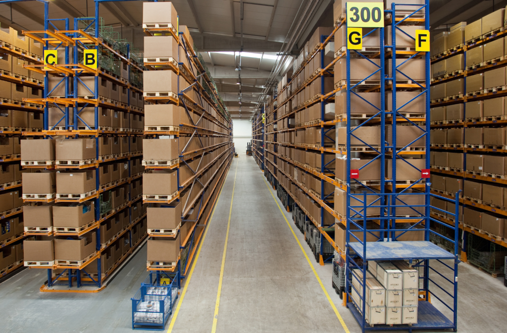 Stacked boxes and pallets stored in a spacious temporary storage structure.